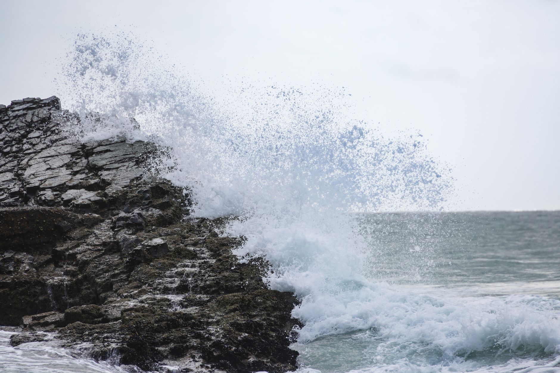 Ocean wave crashing against a rocky Pacific coastline