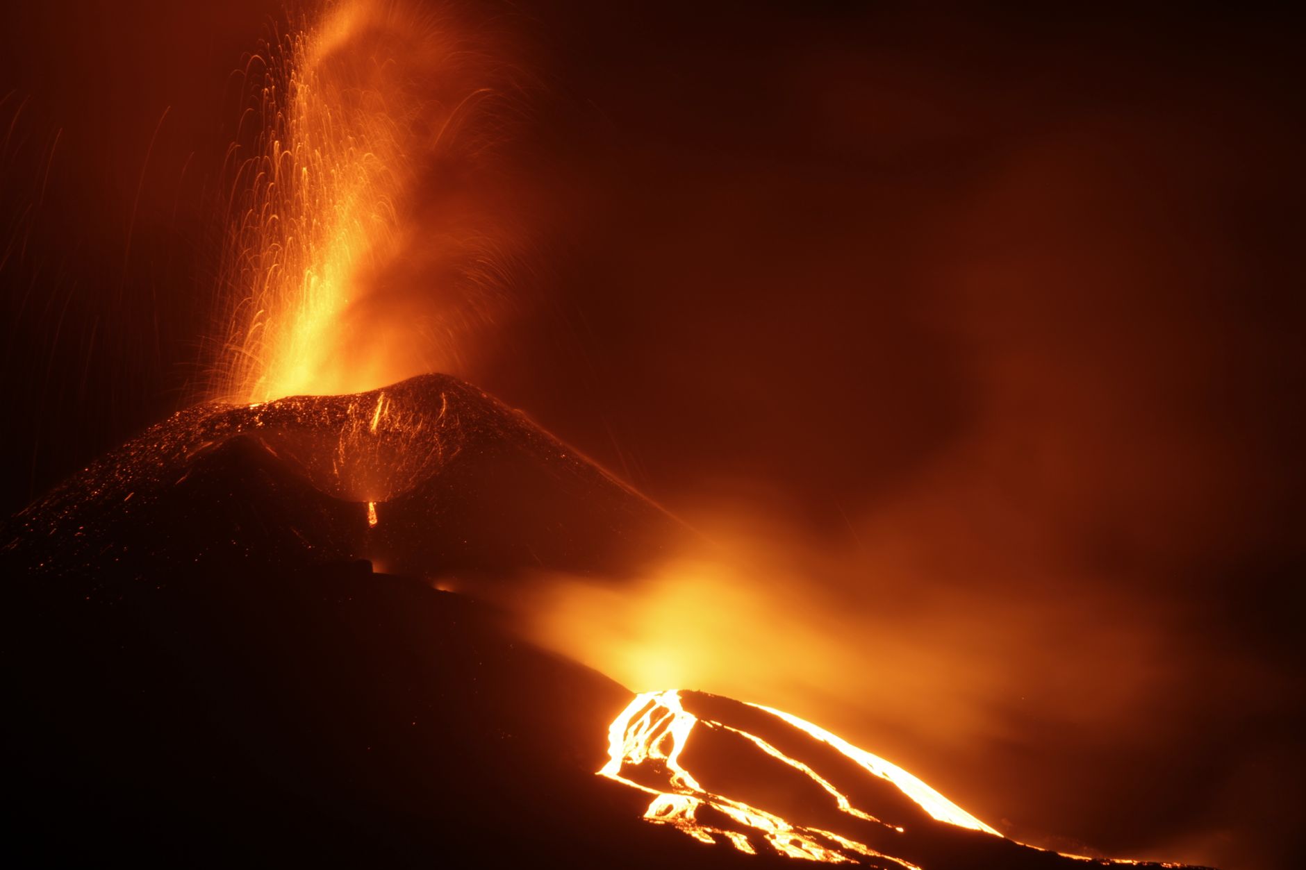 Active volcano erupting with glowing lava at night